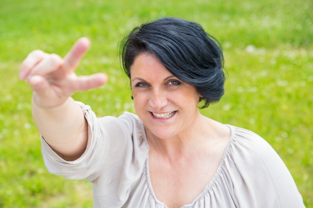 joyful-happy-middle-aged-woman-showing-peace-sign_1262-20581